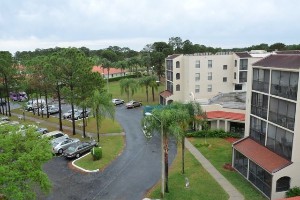Aerial view of a hotel with parking area and palm trees.