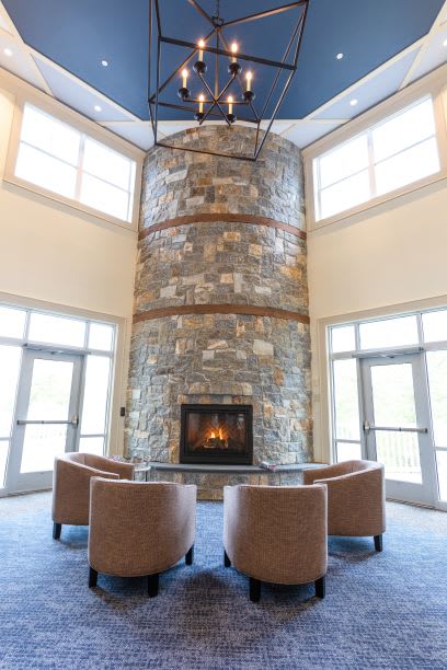 A modern interior with a tall stone fireplace and comfortable seating.