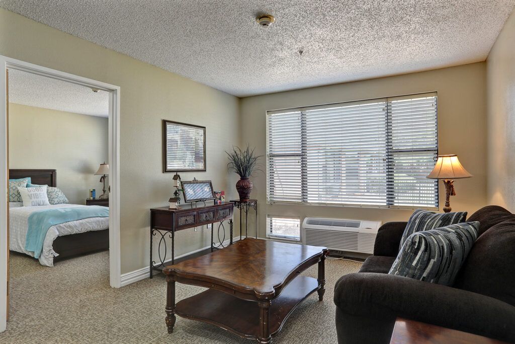 A cozy living room with a coffee table, sofa, and large window providing natural light.