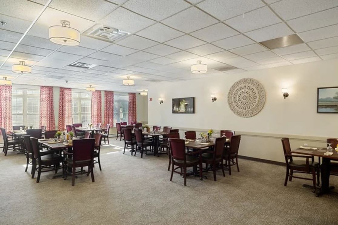 A neat and well-arranged dining room with multiple tables and chairs, featuring warm decor and ambient lighting.