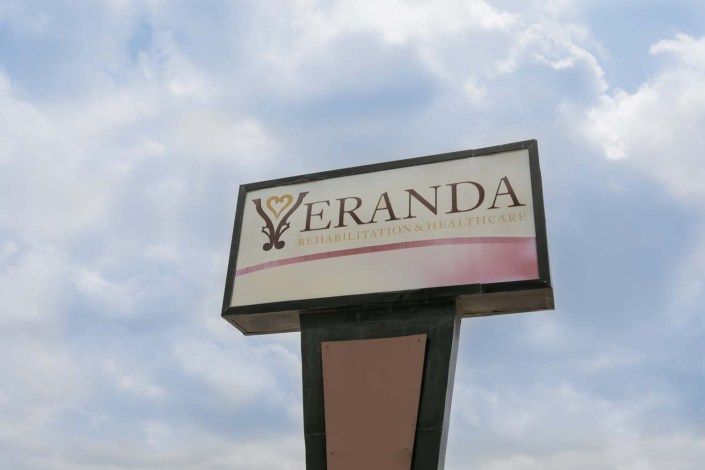 A business sign for 'Veranda' set against a cloudy sky.