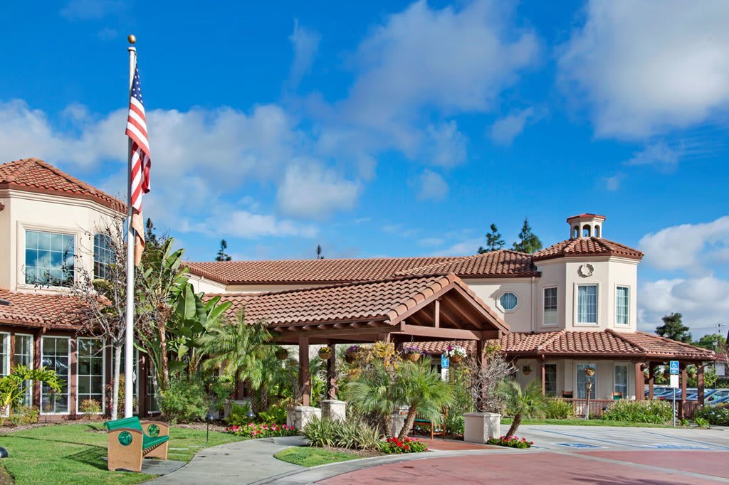 A well-maintained building with a landscaped entrance and a flagpole under a blue sky.