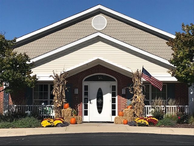 A building entrance decorated for autumn with pumpkins and hay bales.