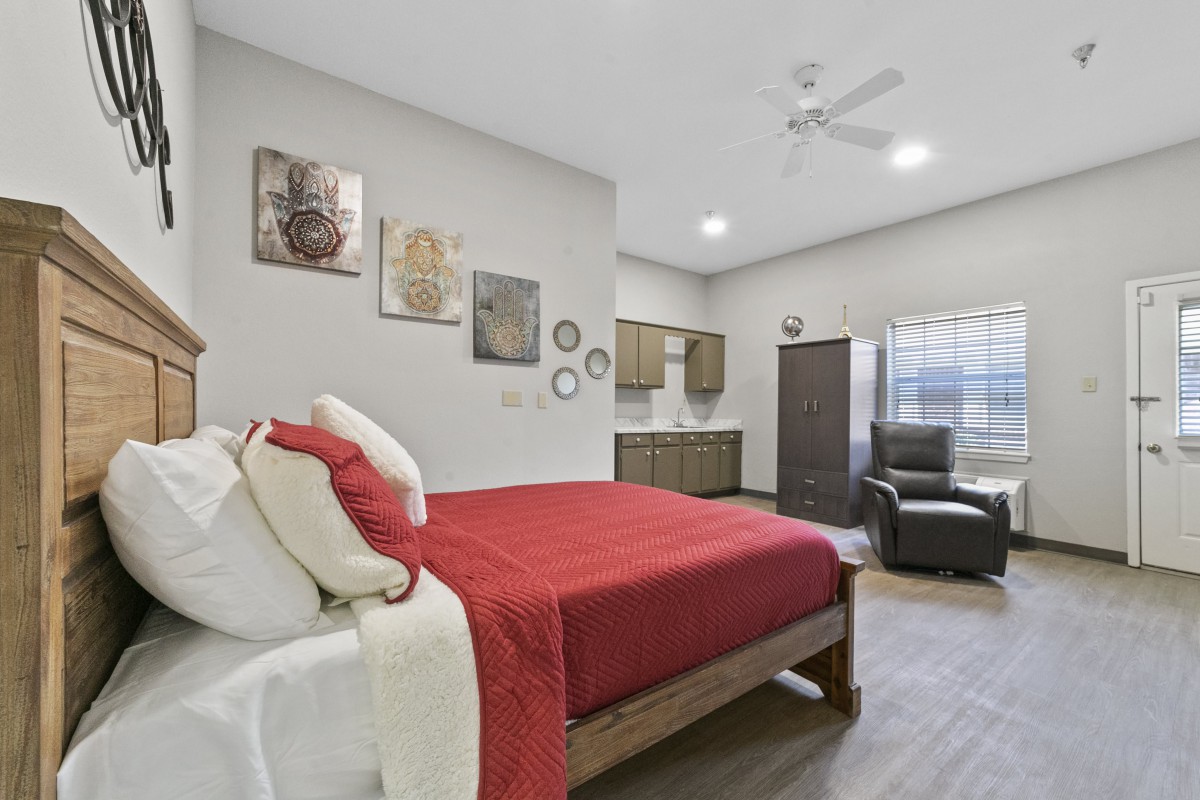 A modern bedroom with red bedding, stylish decor, and a comfortable seating area.