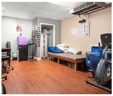 A rehabilitation room equipped with exercise machines and a treatment table.