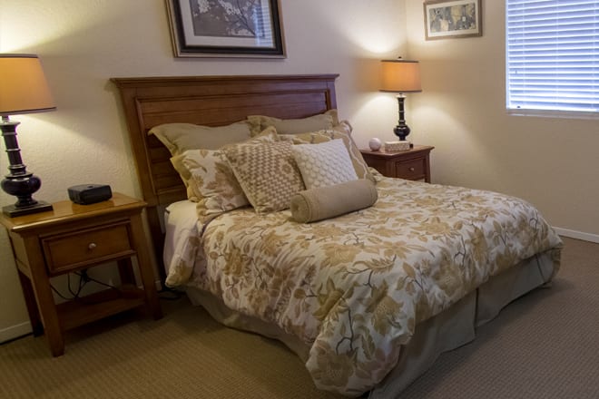 A cozy bedroom with a neatly made bed, warm lighting, and decorative pillows.
