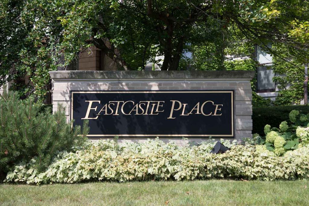 Outdoor sign for Eastcastle Place surrounded by greenery.