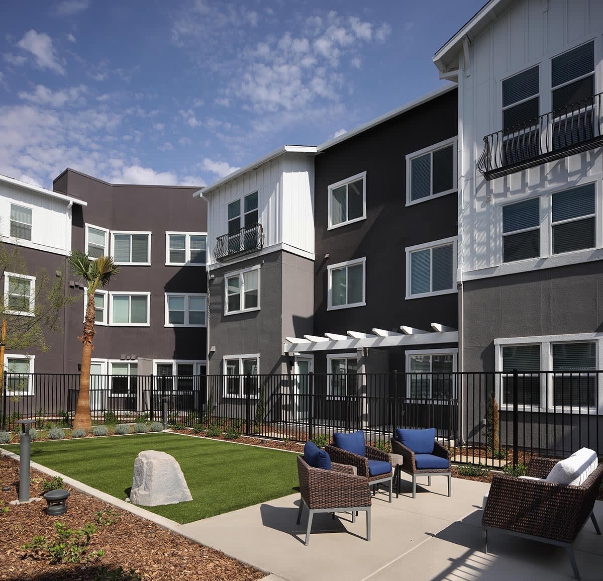 A modern apartment complex with outdoor seating and landscaped areas.