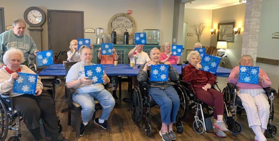 Seniors enjoying a group craft activity, proudly displaying their creations.