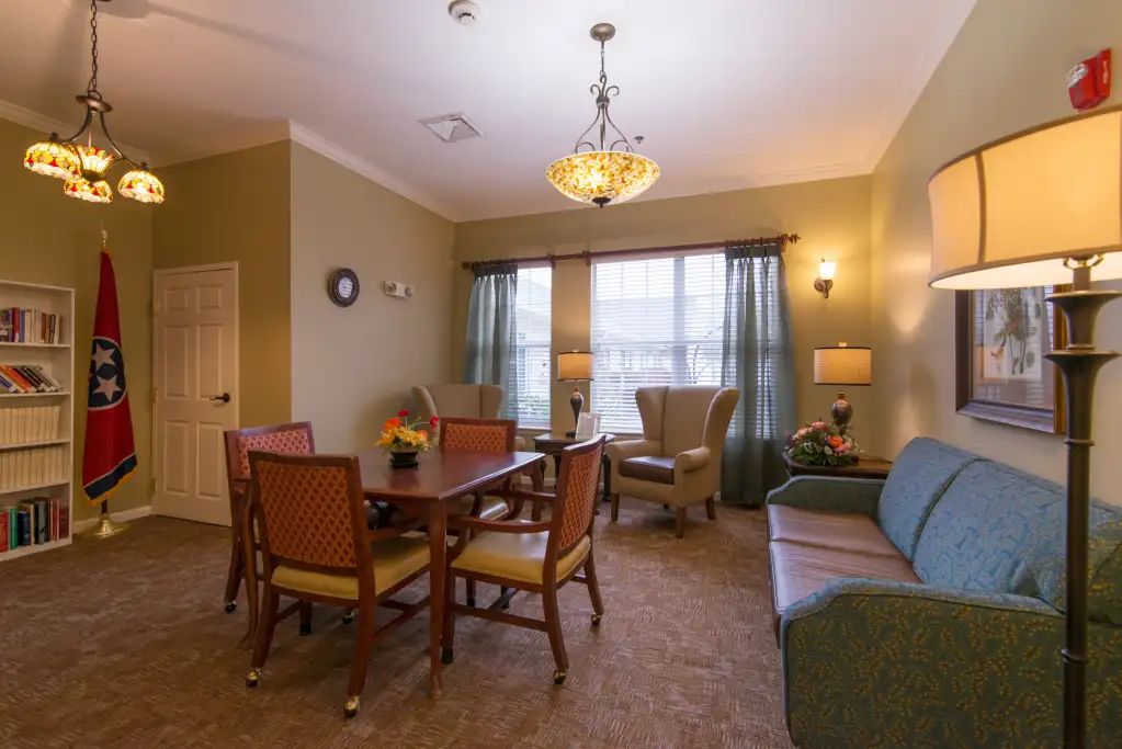 A cozy living and dining area with traditional furnishings, including a dining table, chairs, a sofa, and a chandelier.