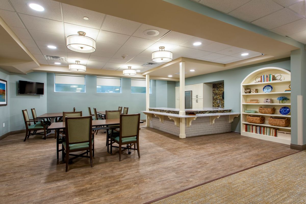 A spacious dining area with tables and chairs, featuring elegant lighting and warm decor.