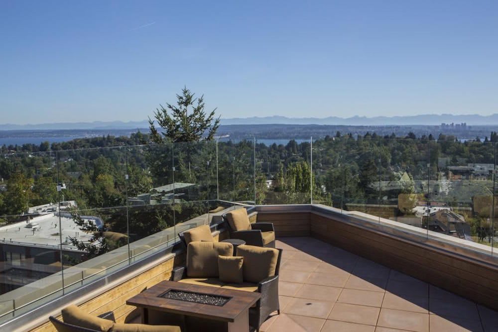 A scenic terrace with comfortable seating offers a stunning view of the ocean and surrounding greenery.