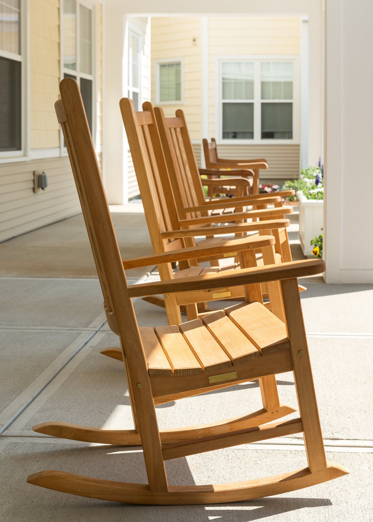 A row of wooden rocking chairs on a sunny porch.