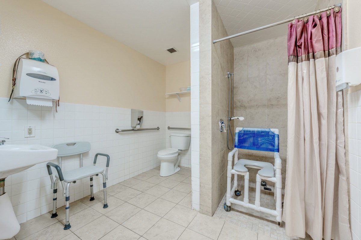 An accessible bathroom equipped with a shower chair and handrails for safety.