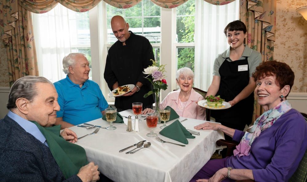 A group of seniors enjoying a meal together while being served by friendly waitstaff.