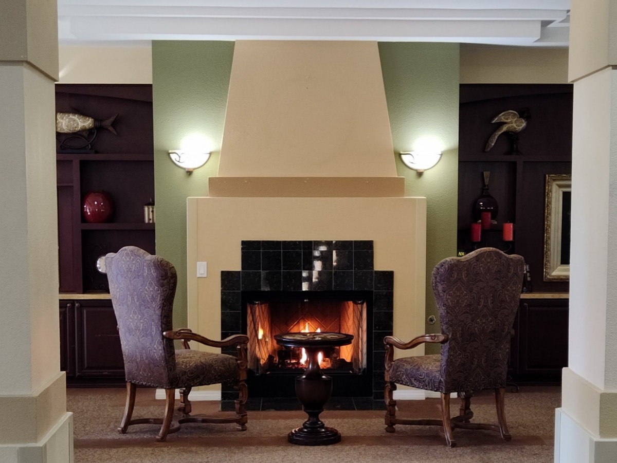 A cozy living room with a burning fireplace flanked by two comfortable chairs.