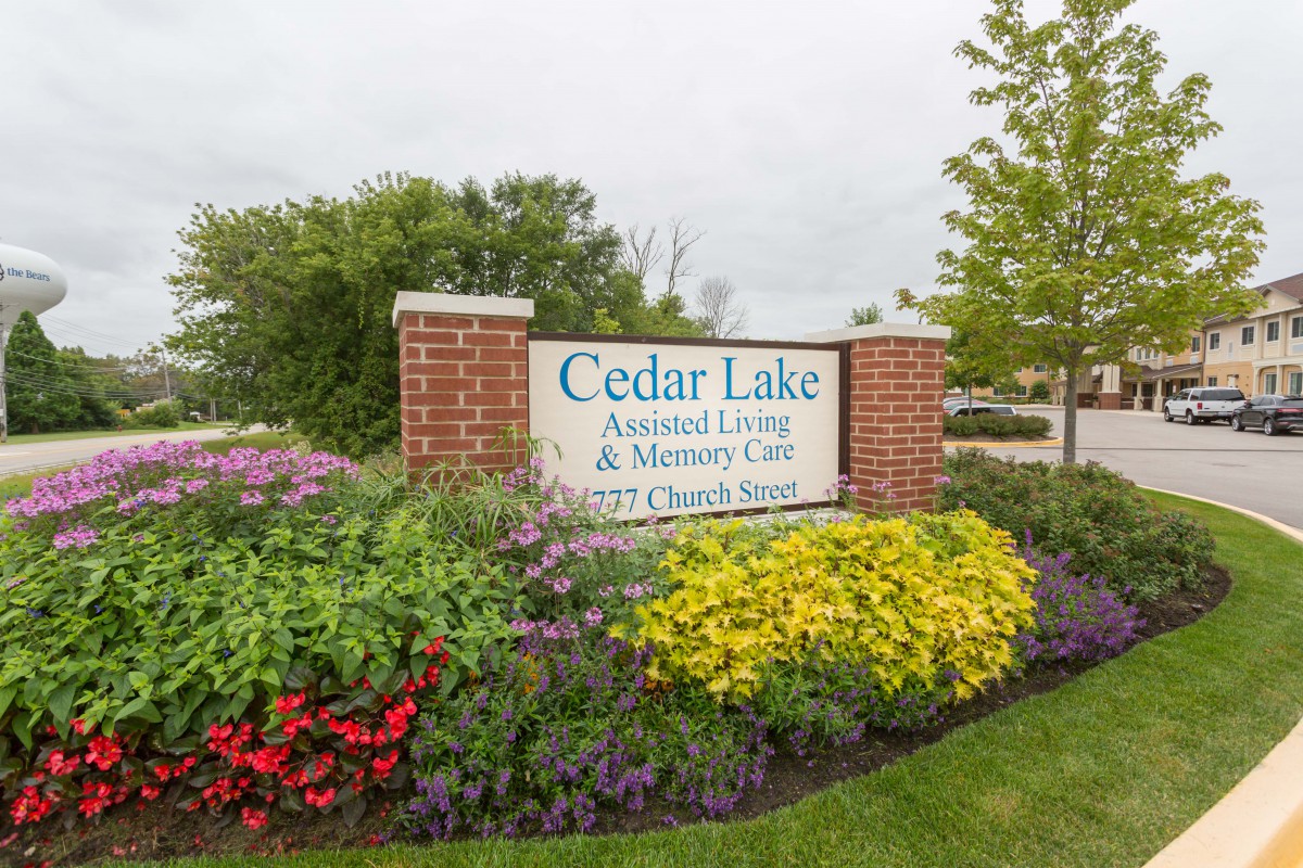 Entrance sign for Cedar Lake Assisted Living & Memory Care surrounded by landscaped flowers.