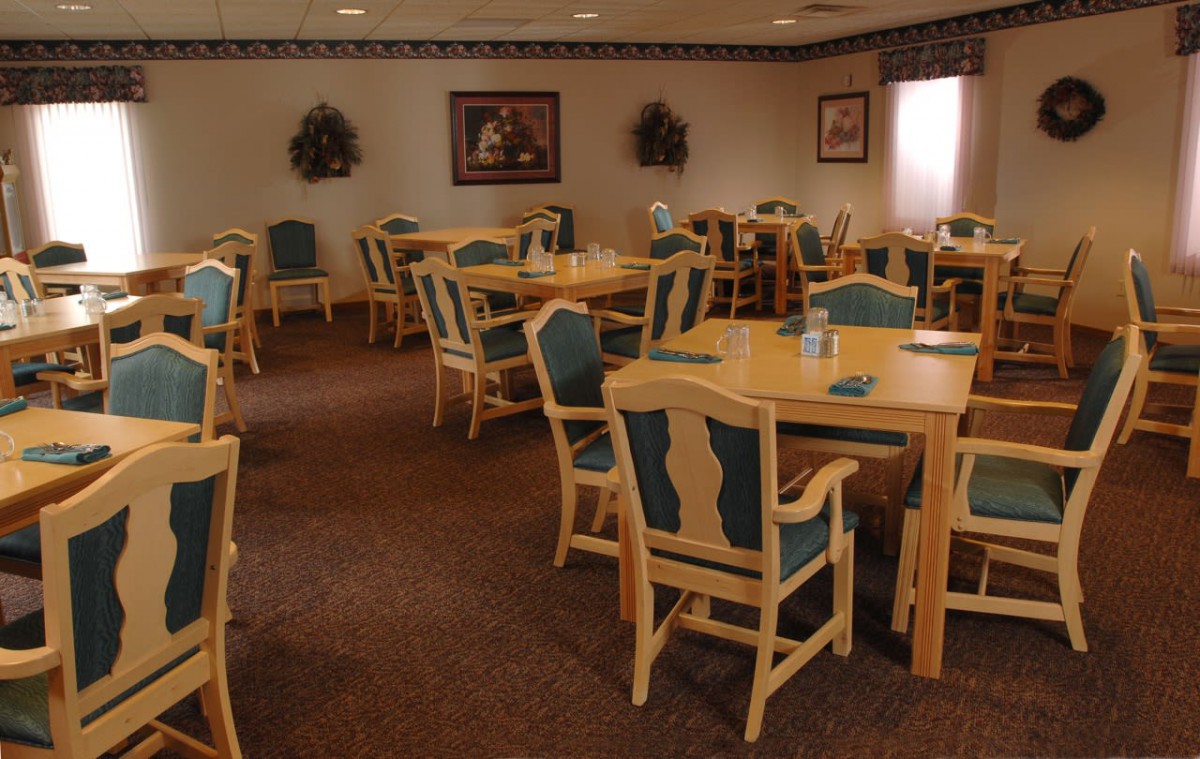 An empty dining room with wooden tables and chairs arranged neatly.