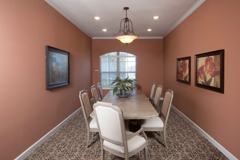 A well-decorated dining room featuring a long table, upholstered chairs, and wall art.