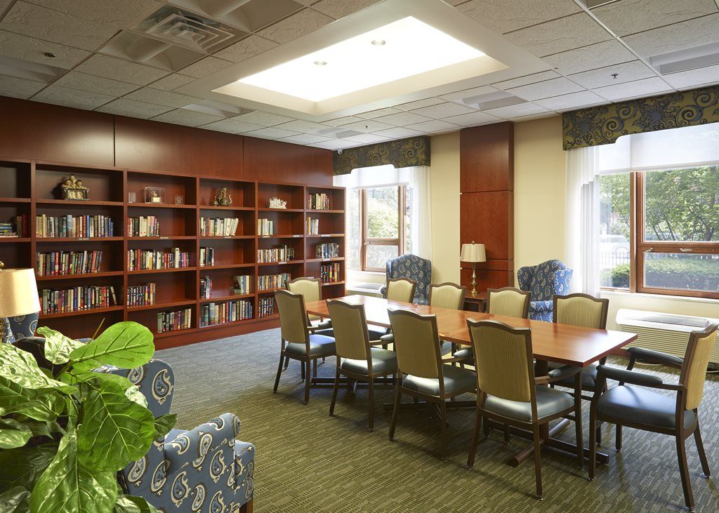 A well-lit meeting room with a conference table and chairs, surrounded by bookshelves.