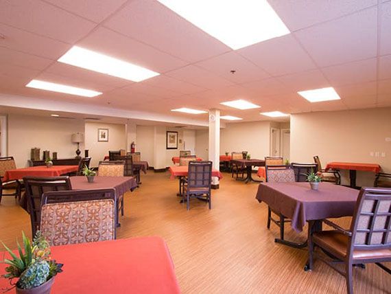 A spacious dining room with tables and chairs arranged neatly under bright ceiling lights.
