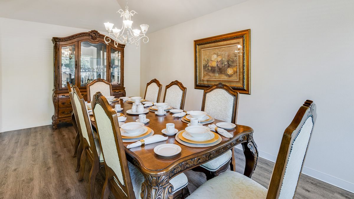 An elegantly set dining room table with a chandelier and classic decor.