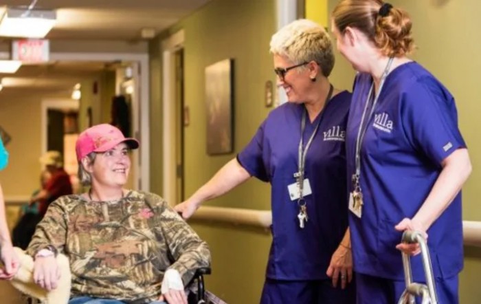 Nurses interacting with a patient in a wheelchair at a healthcare facility.