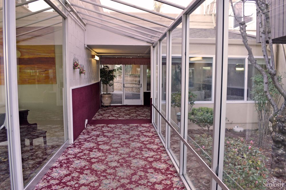 A carpeted hallway with glass walls on either side, leading to a door at the end.
