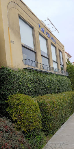 An exterior view of a building featuring large windows and lush greenery.