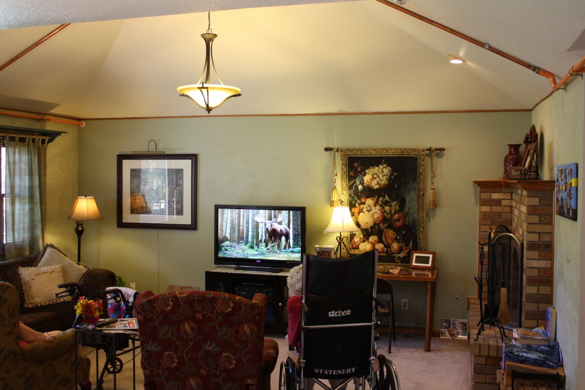 A cozy living room with a television, wheelchair, and various decor items.