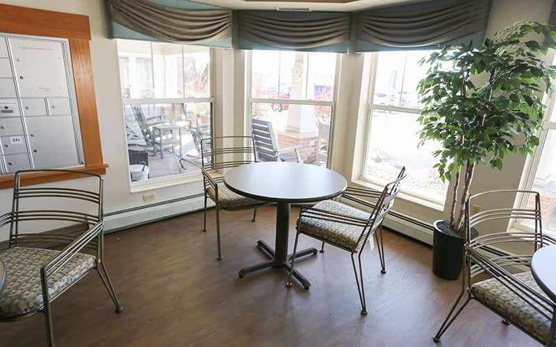 A cozy dining area with a round table and four chairs by large windows.