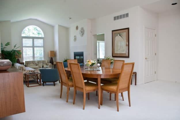 A modern dining area with a wooden table and six chairs in a well-lit, open living space.