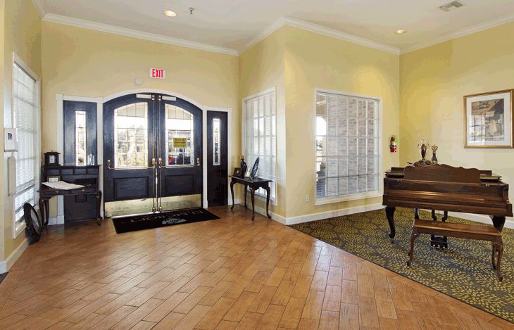 A spacious lobby area featuring a piano and double doors leading to the outside.