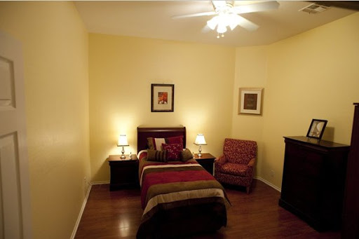 A cozy and well-lit bedroom featuring a single bed, decorative artwork, and comfortable seating.