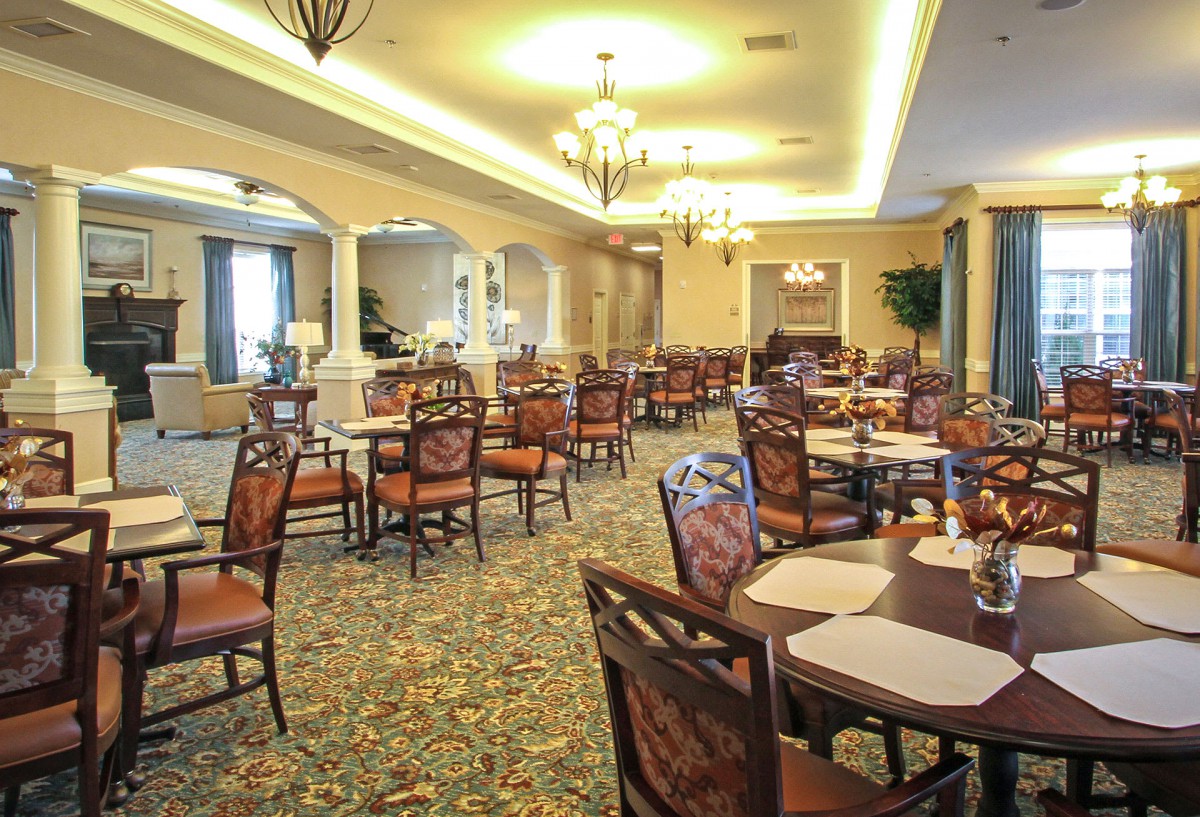 An elegant restaurant dining room with neatly arranged tables and classic chandeliers.