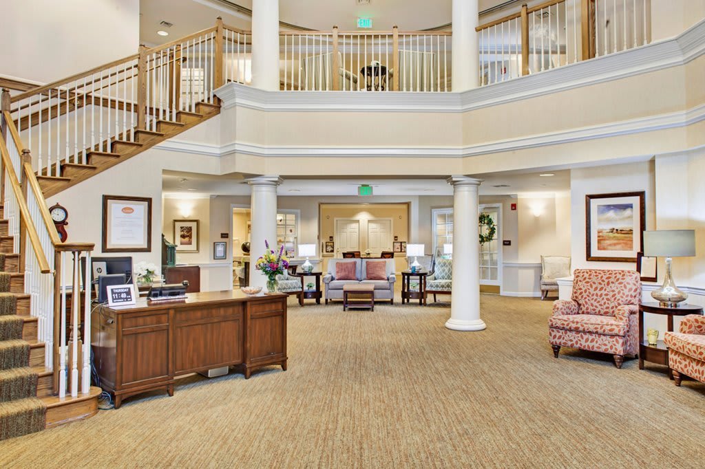 A spacious and elegant lobby featuring a reception desk, staircases, and seating area.