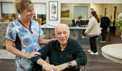 A caregiver shares a warm moment with an elderly resident at a nursing home.