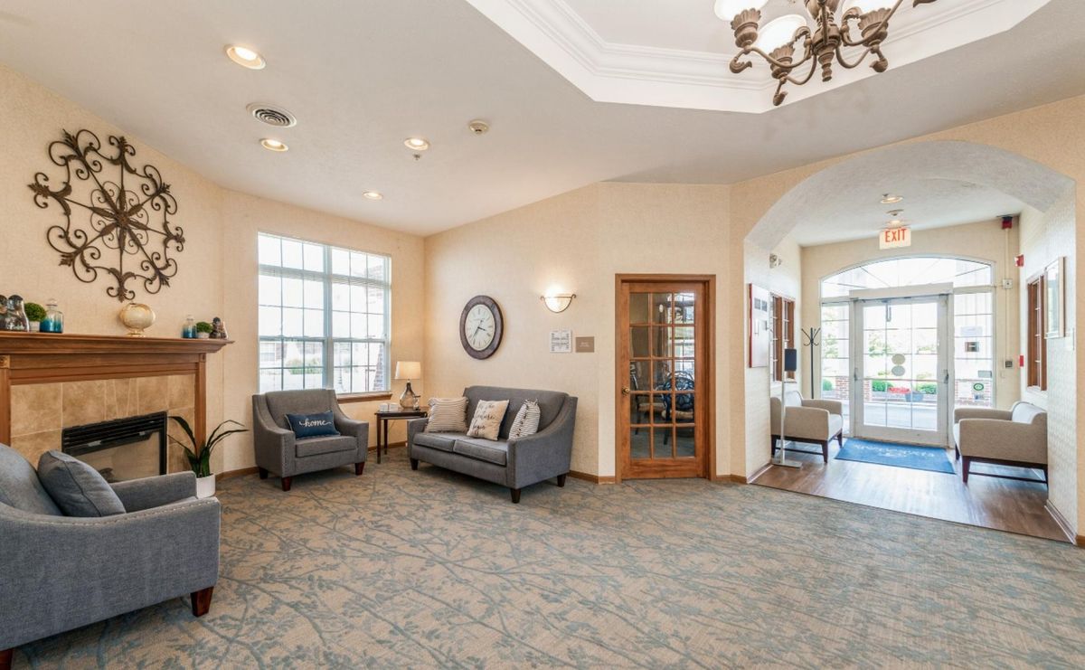 A cozy lobby featuring comfortable sofas, a chandelier, and large windows providing ample natural light.
