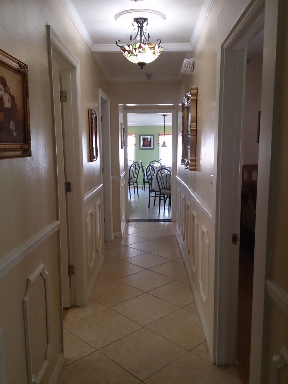 A view of a well-lit hallway leading to a dining area in a home.