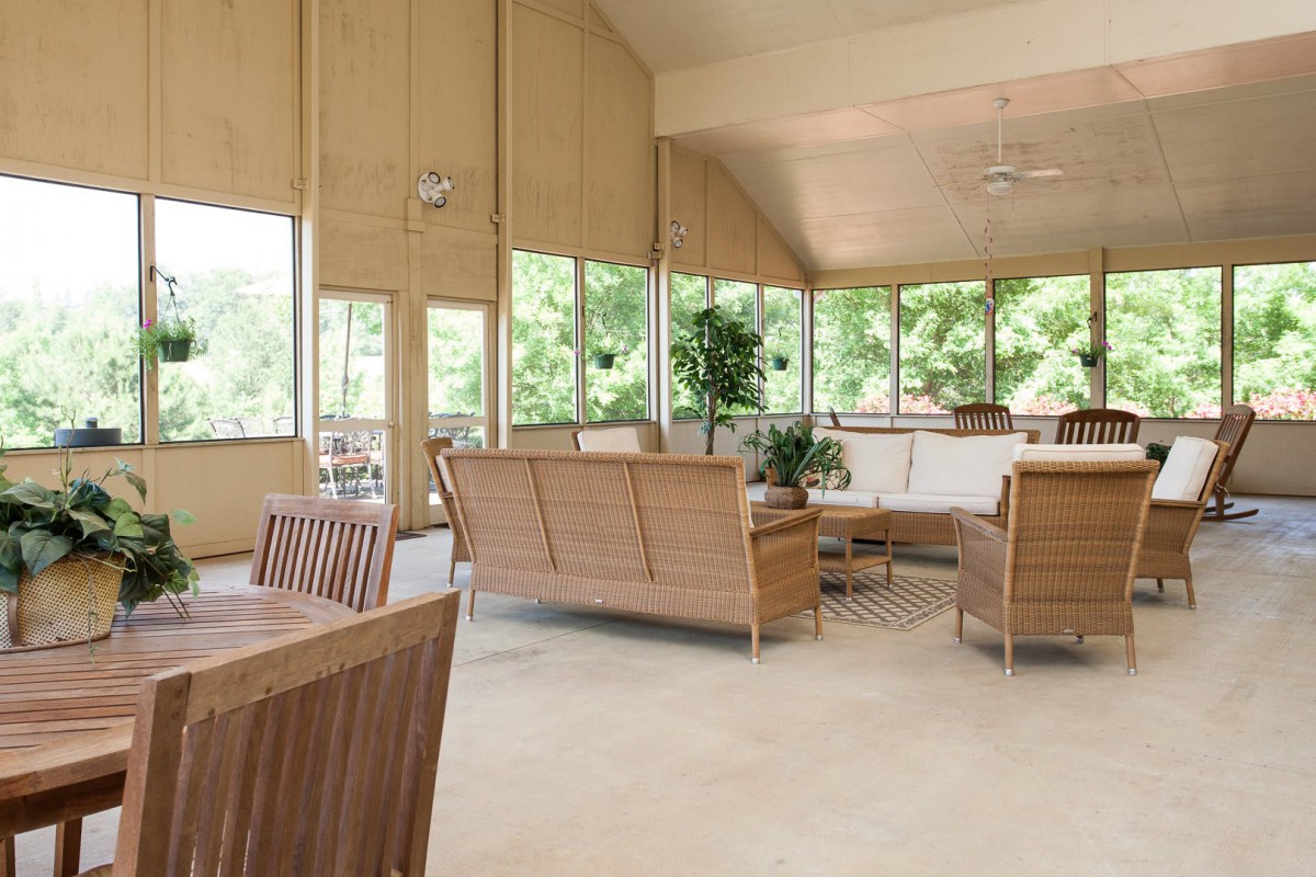 A modern living room featuring wood furniture and large windows, allowing ample natural light to fill the spacious area.