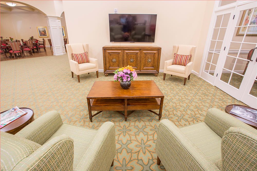 A cozy living room with comfortable seating, a large television, and a coffee table adorned with a floral arrangement.