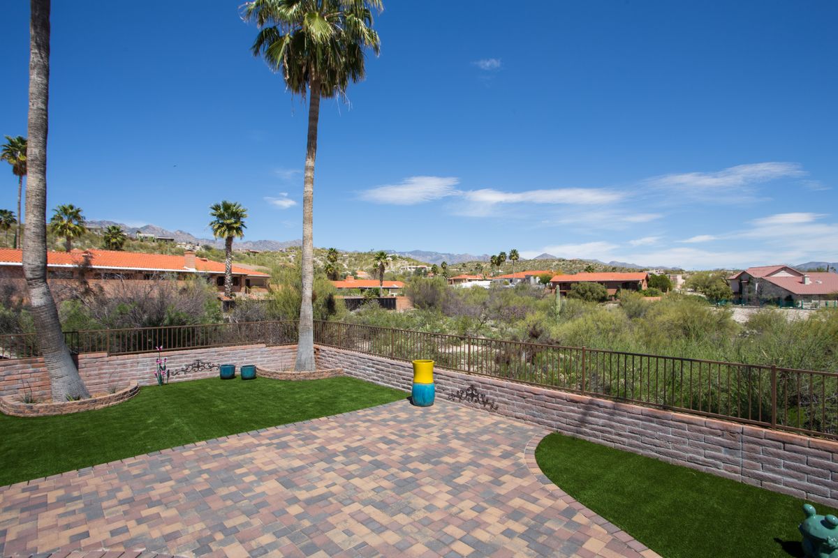 A sunny patio area with a palm tree and views of surrounding desert landscape and buildings.