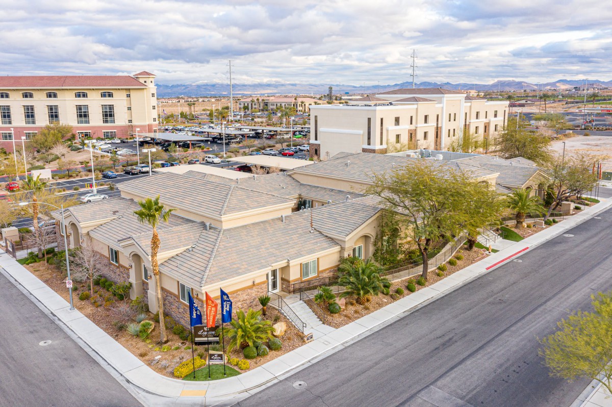 An aerial view of a building complex with a parking lot and desert landscape in the background.
