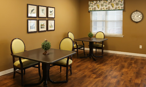 A cozy dining area featuring two tables with chairs, framed artwork on the wall, and a bright window.