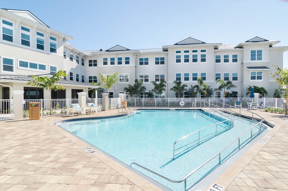 A residential complex with a swimming pool and palm trees on a sunny day.