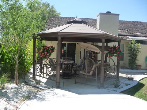 A cozy outdoor gazebo with seating and hanging plants, perfect for relaxation.
