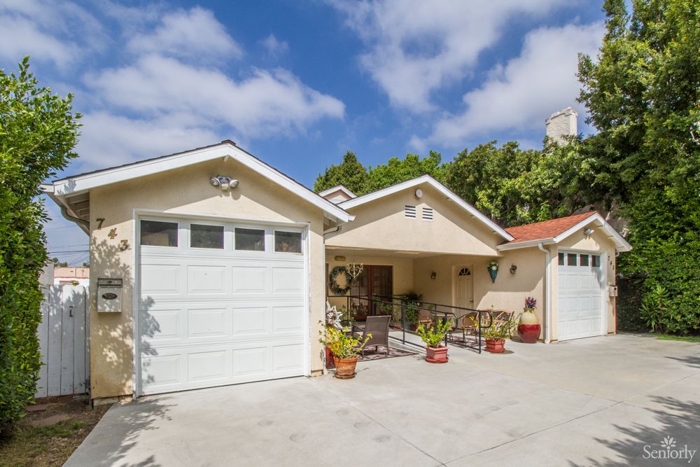 A residential house with a garage and driveway on a sunny day.