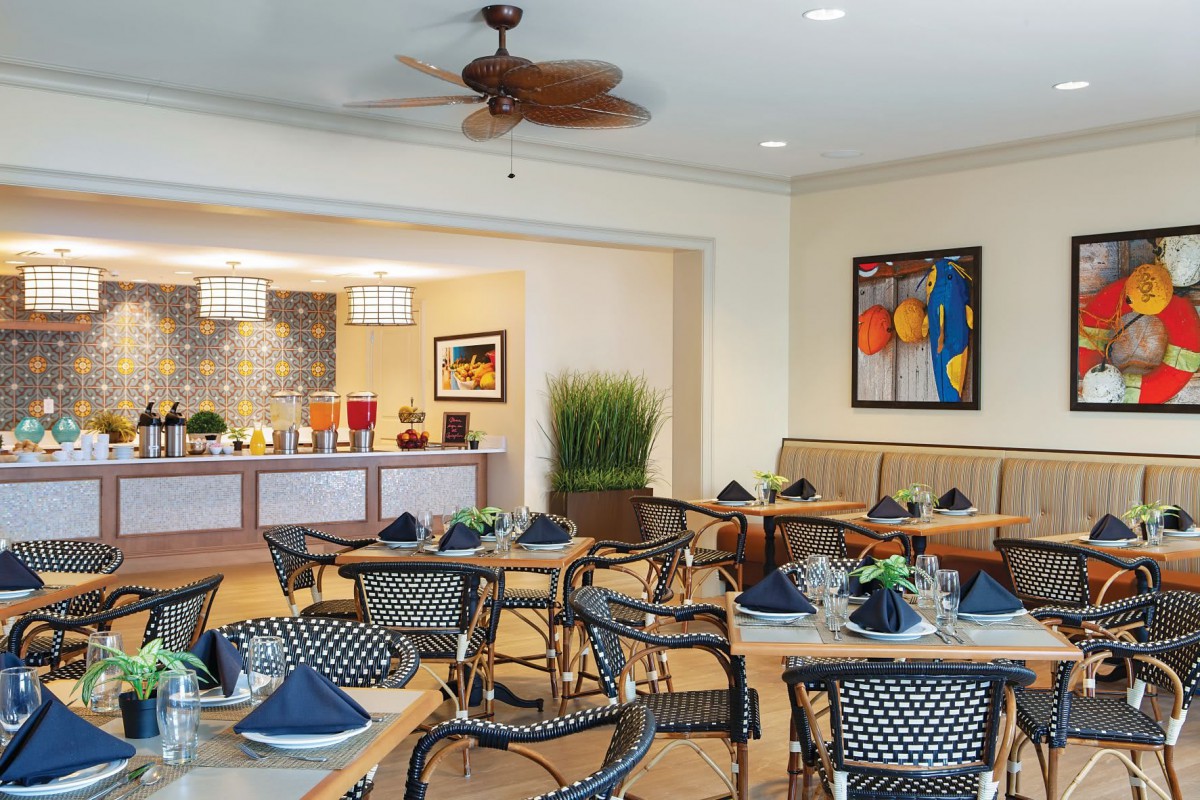 A well-decorated restaurant interior with neatly arranged tables and chairs, adorned with artwork and table settings.