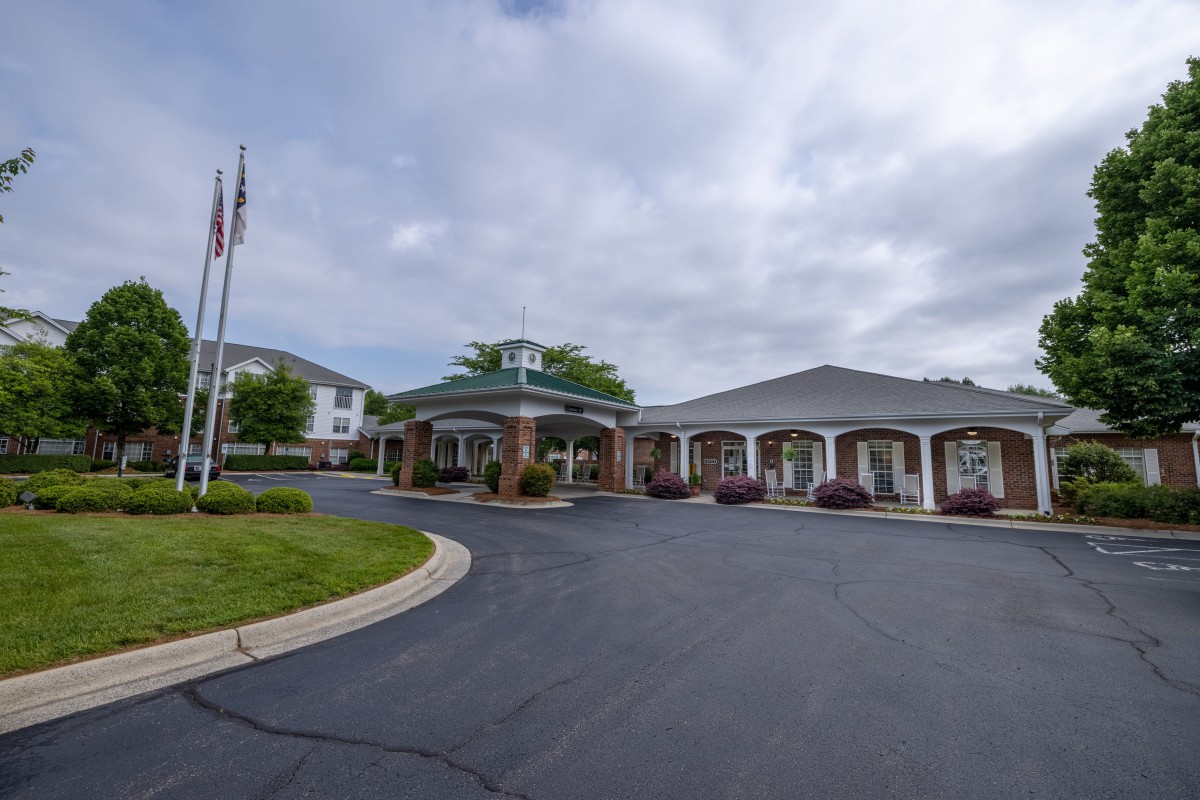 A building with flags and a curved driveway under a cloudy sky.