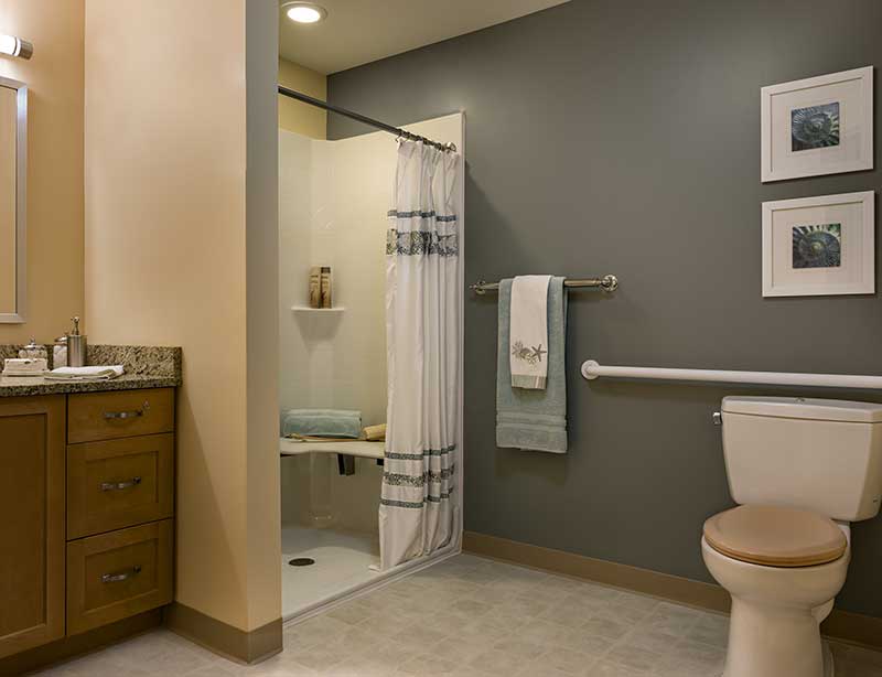 A modern bathroom with a shower, toilet, and towel rack.